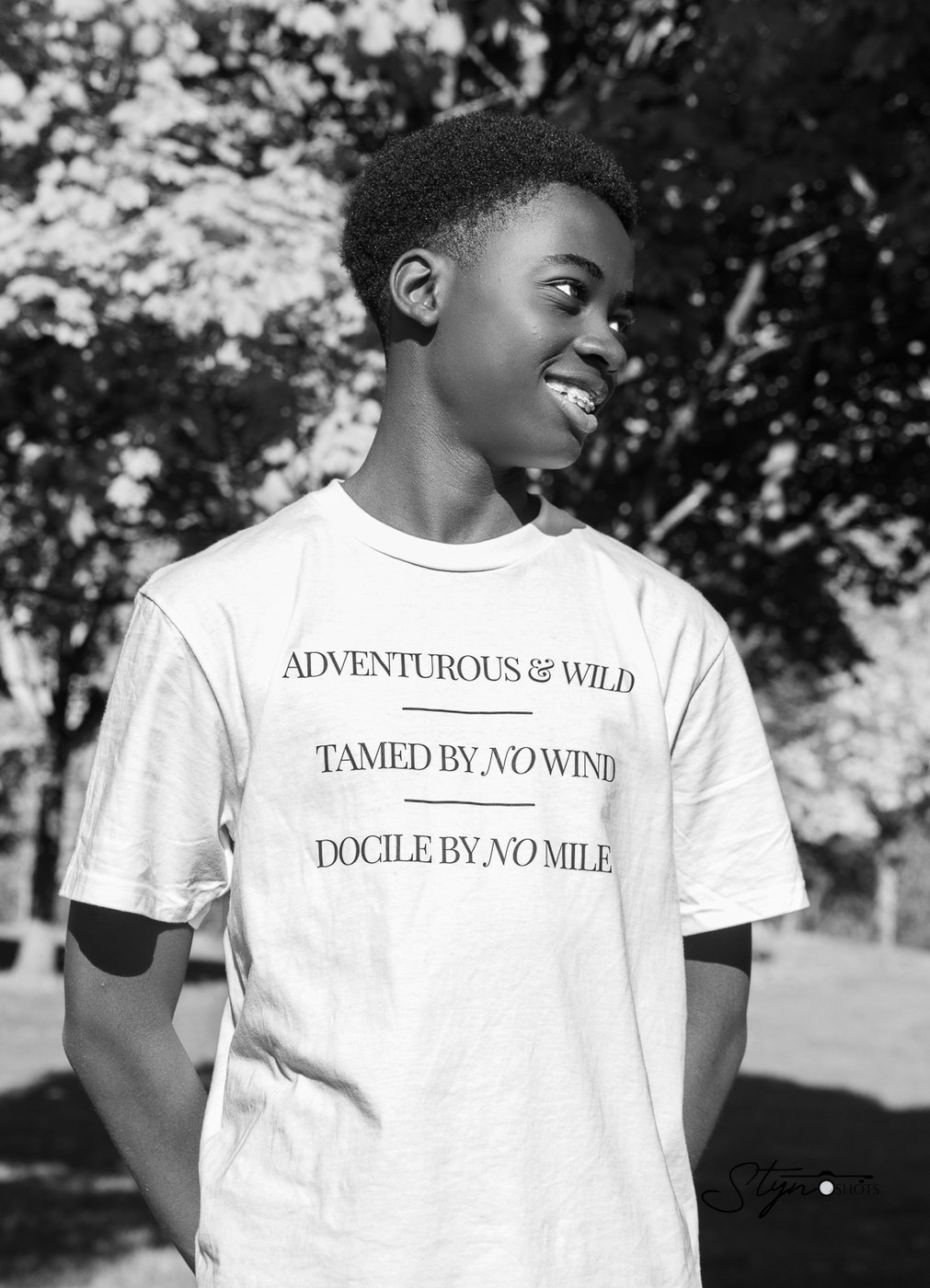 A young model wearing the Adventurous and Wild tee outdoors